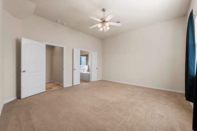 unfurnished bedroom featuring ceiling fan, ensuite bathroom, and light colored carpet