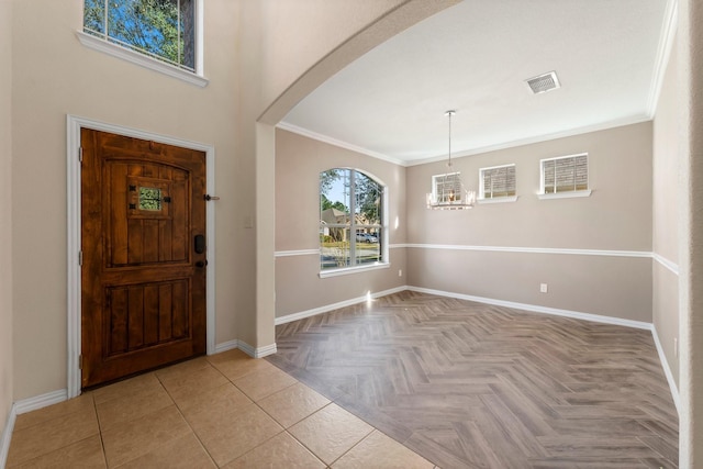 entrance foyer featuring an inviting chandelier, ornamental molding, and light parquet flooring