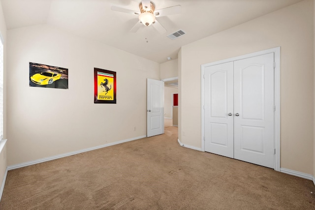 unfurnished bedroom featuring light carpet, ceiling fan, vaulted ceiling, and a closet