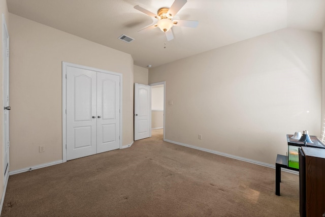 unfurnished bedroom featuring lofted ceiling, light colored carpet, a closet, and ceiling fan