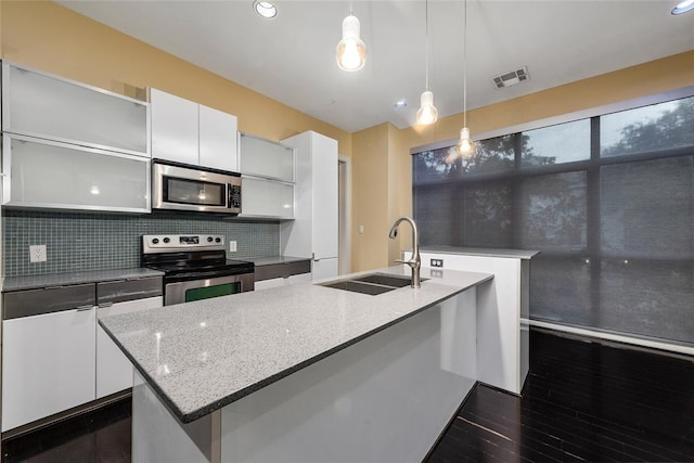 kitchen with sink, white cabinets, hanging light fixtures, a kitchen island with sink, and stainless steel appliances