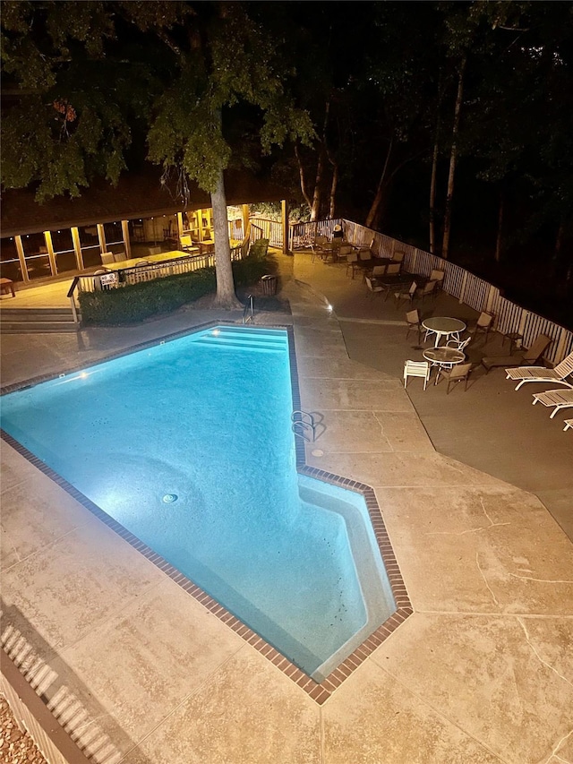 pool at night featuring a patio area