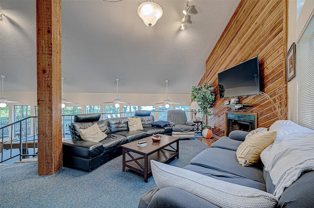 living room with carpet flooring, a textured ceiling, ceiling fan, and wood walls