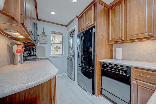 kitchen with light hardwood / wood-style flooring, stacked washer and clothes dryer, tasteful backsplash, ornamental molding, and black appliances