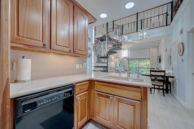 kitchen with sink, black dishwasher, kitchen peninsula, light hardwood / wood-style floors, and backsplash