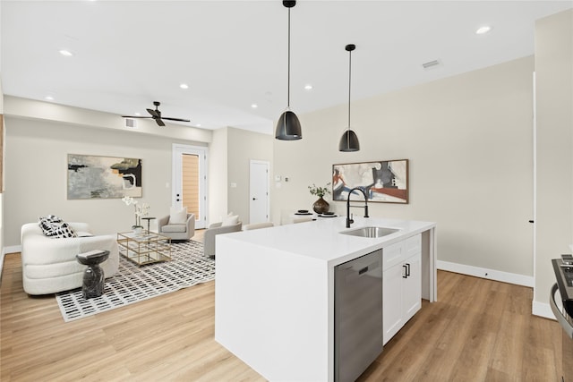 kitchen featuring dishwasher, an island with sink, sink, white cabinets, and hanging light fixtures