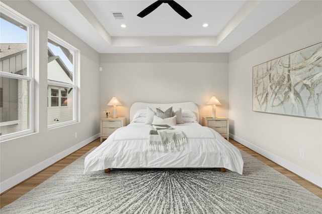 bedroom featuring hardwood / wood-style floors, a tray ceiling, and ceiling fan