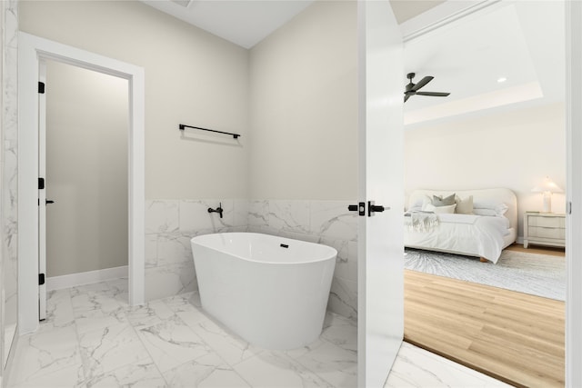 bathroom with a bathing tub, tile walls, and ceiling fan