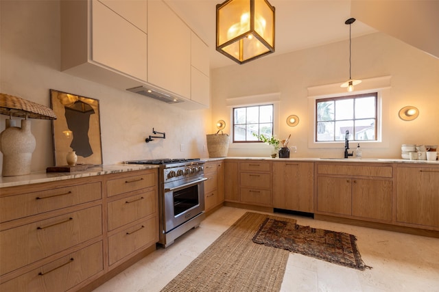 kitchen with light brown cabinetry, sink, tasteful backsplash, high end range, and hanging light fixtures