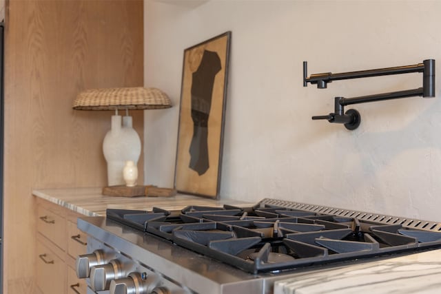 interior details with stovetop and light brown cabinets