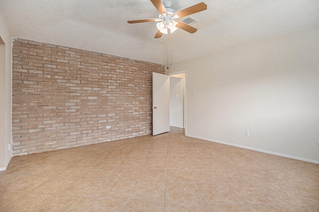 unfurnished room featuring light tile patterned flooring, ceiling fan, brick wall, and a textured ceiling