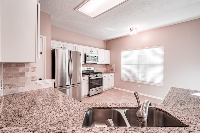 kitchen featuring stainless steel appliances, sink, white cabinets, and light stone counters