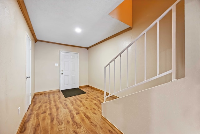 foyer entrance with wood-type flooring and crown molding