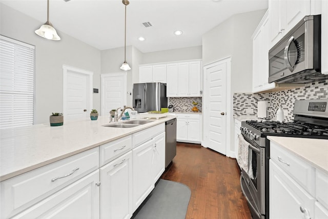 kitchen with decorative light fixtures, sink, white cabinets, stainless steel appliances, and dark wood-type flooring