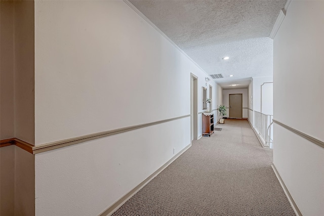 hall featuring ornamental molding, light colored carpet, and a textured ceiling