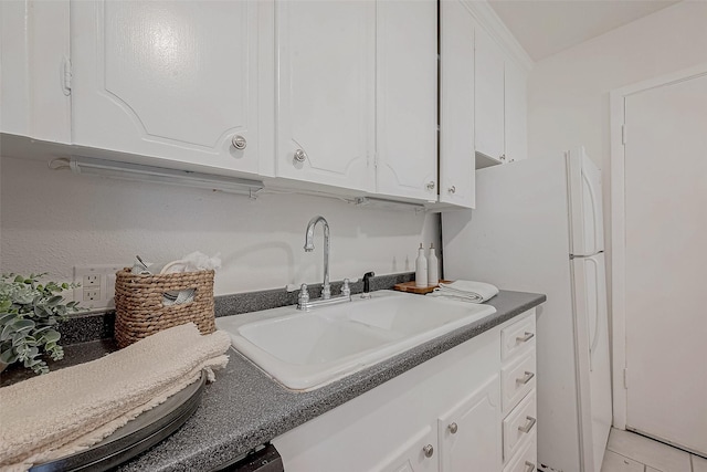 kitchen with white cabinetry, sink, white fridge, and light tile patterned floors