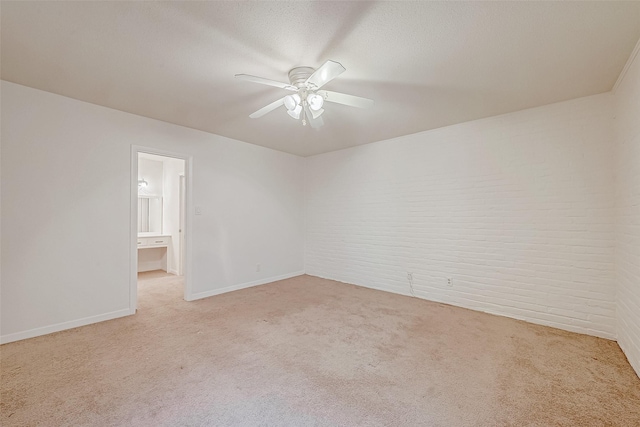 empty room featuring brick wall, light carpet, a textured ceiling, and ceiling fan