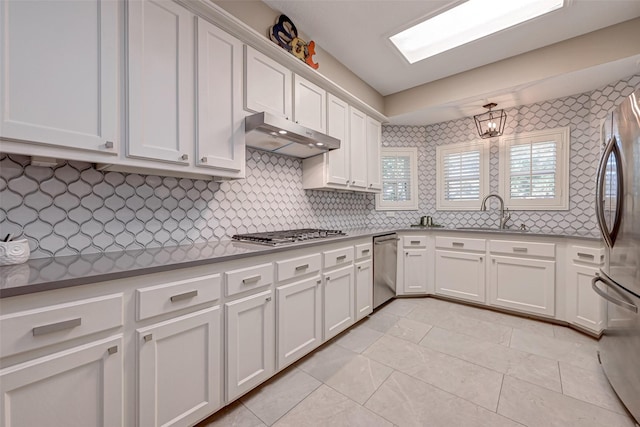 kitchen featuring light tile patterned flooring, appliances with stainless steel finishes, sink, white cabinets, and decorative backsplash