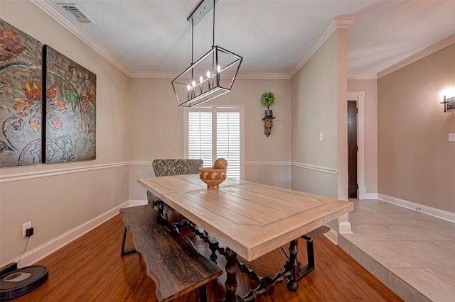 dining area with crown molding, a chandelier, and hardwood / wood-style flooring