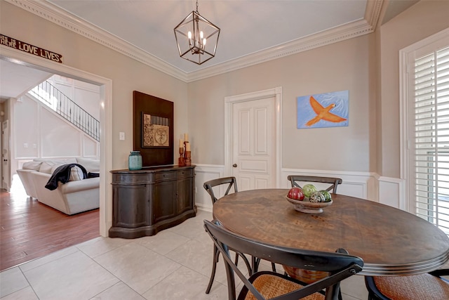 tiled dining space featuring ornamental molding and a chandelier