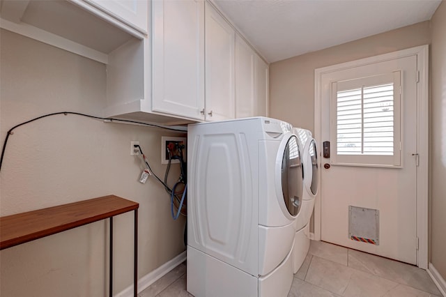 laundry area featuring cabinet space, light tile patterned floors, baseboards, and independent washer and dryer