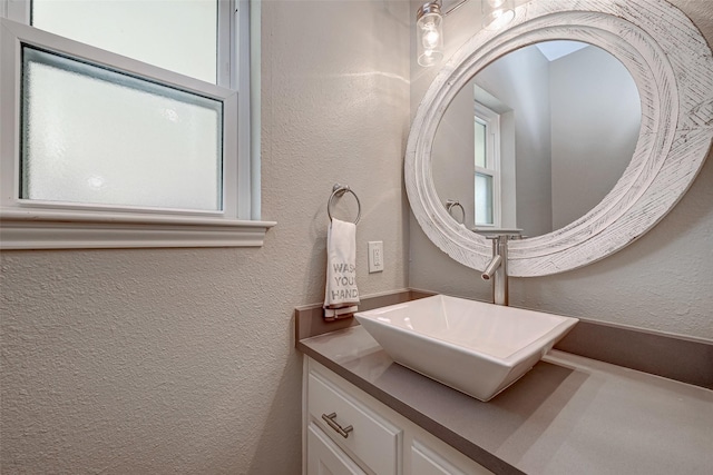 bathroom featuring a healthy amount of sunlight, vanity, and a textured wall