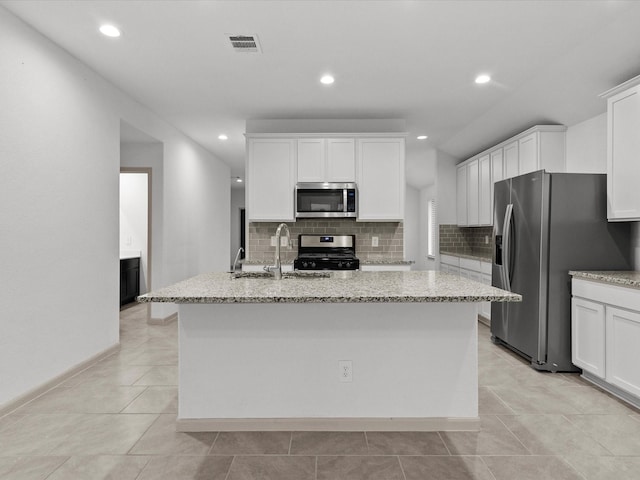 kitchen with white cabinetry, light stone countertops, an island with sink, and appliances with stainless steel finishes