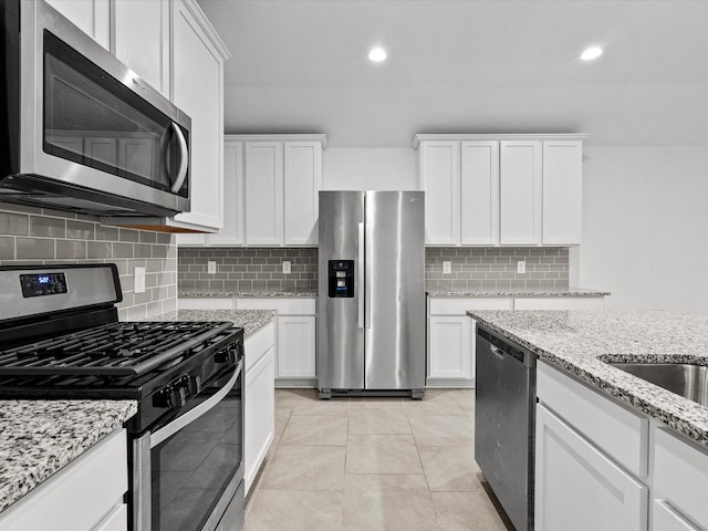 kitchen featuring backsplash, light tile patterned flooring, white cabinets, and appliances with stainless steel finishes