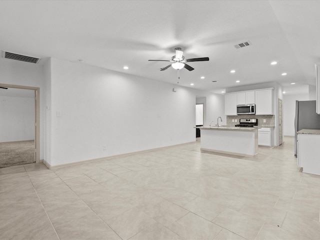 unfurnished living room featuring light tile patterned floors, sink, and ceiling fan