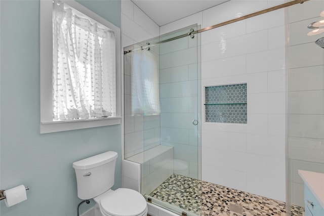 bathroom featuring a shower with door and toilet