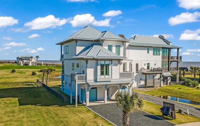 rear view of property with a water view, a balcony, and a yard