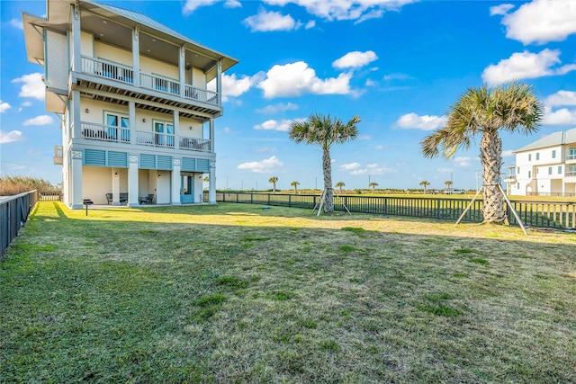 rear view of house with a balcony and a yard