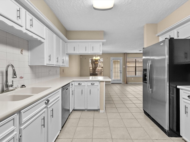 kitchen with sink, kitchen peninsula, stainless steel appliances, decorative backsplash, and white cabinets