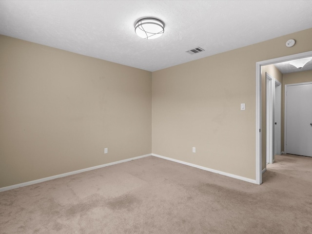 unfurnished room featuring light colored carpet and a textured ceiling