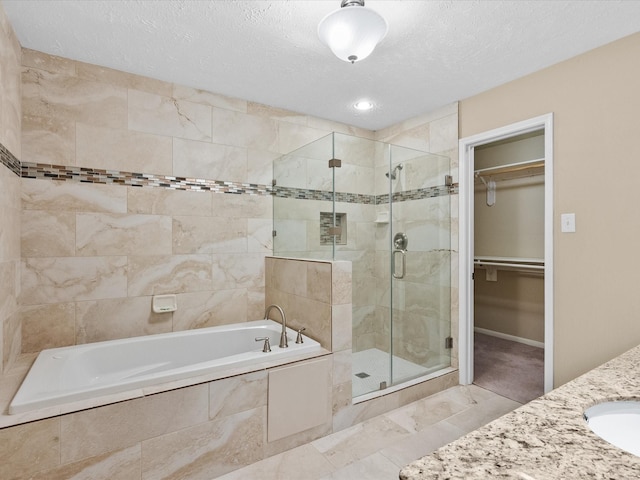 bathroom featuring shower with separate bathtub, sink, and a textured ceiling