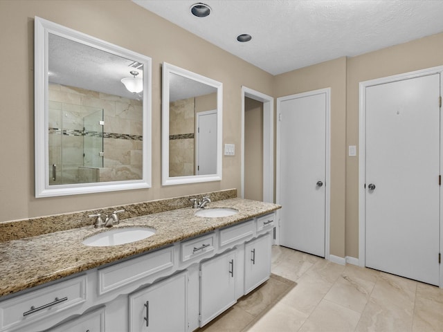 bathroom featuring vanity, an enclosed shower, and a textured ceiling