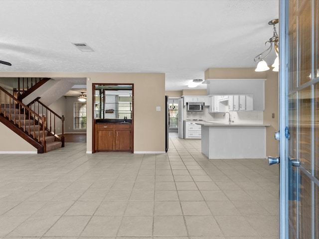 kitchen featuring sink, white cabinetry, hanging light fixtures, ceiling fan, and backsplash