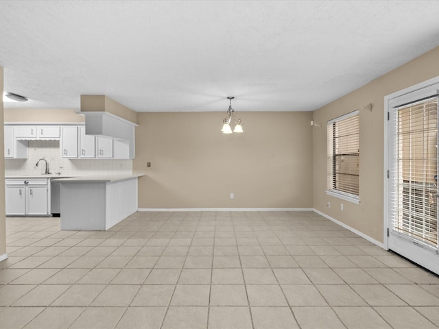 kitchen featuring tasteful backsplash, decorative light fixtures, a chandelier, light tile patterned floors, and white cabinets