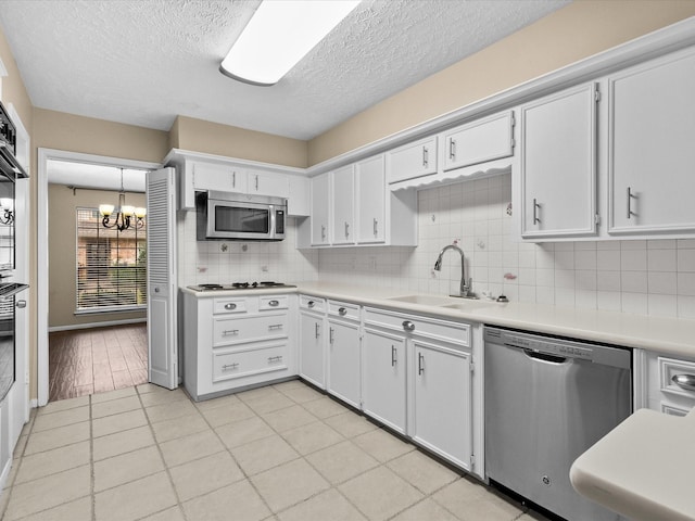 kitchen with sink, white cabinetry, tasteful backsplash, decorative light fixtures, and stainless steel appliances