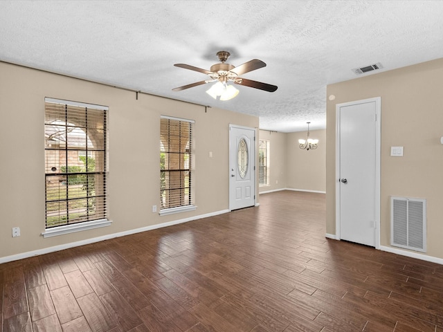 empty room with dark wood-type flooring, ceiling fan with notable chandelier, and a textured ceiling