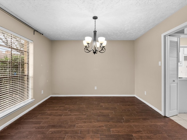 unfurnished dining area featuring an inviting chandelier and a textured ceiling