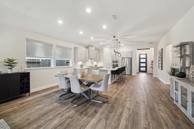 dining space with a healthy amount of sunlight, sink, a notable chandelier, and light hardwood / wood-style flooring