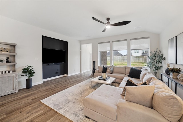 living room featuring wood-type flooring, ceiling fan, and vaulted ceiling