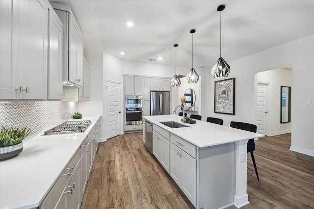 kitchen featuring sink, a kitchen breakfast bar, stainless steel appliances, a kitchen island with sink, and backsplash