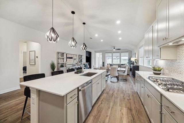 kitchen featuring sink, a breakfast bar area, a center island with sink, appliances with stainless steel finishes, and decorative backsplash