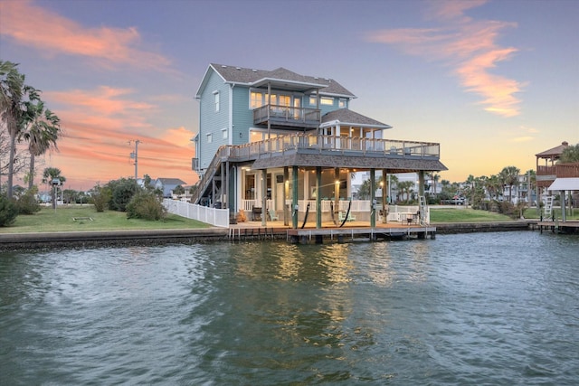 back house at dusk with a balcony and a water view