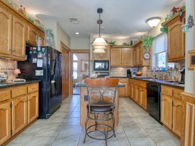 kitchen with a healthy amount of sunlight, a kitchen island, sink, and black appliances