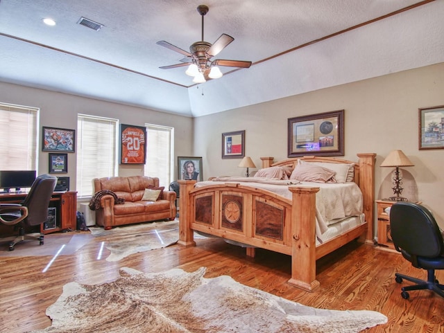 bedroom with hardwood / wood-style flooring, vaulted ceiling, a textured ceiling, and ceiling fan