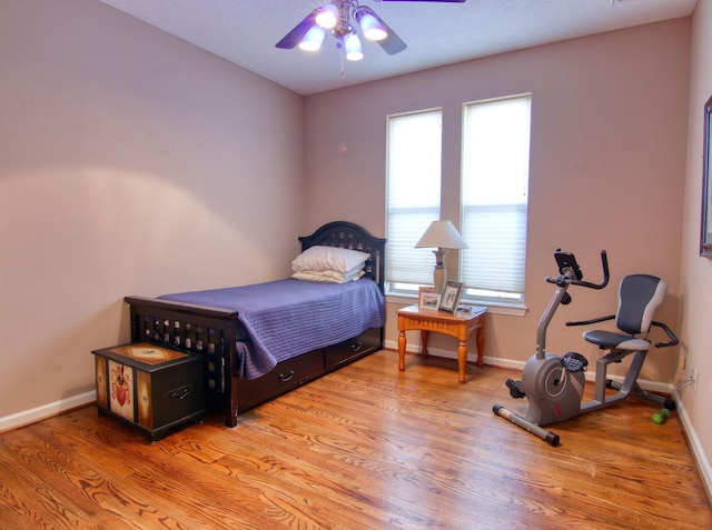 bedroom with ceiling fan, light hardwood / wood-style floors, and multiple windows