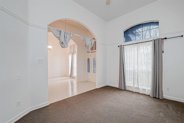 empty room featuring ceiling fan with notable chandelier and light tile patterned floors